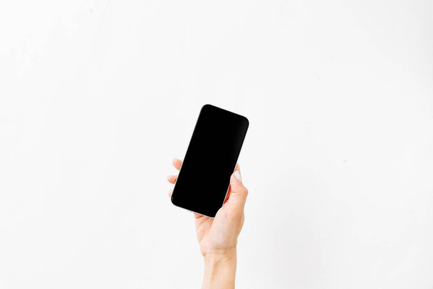 kobieca ręka trzymająca czarny smartfon na białym tle - Zdjęcie, obraz
