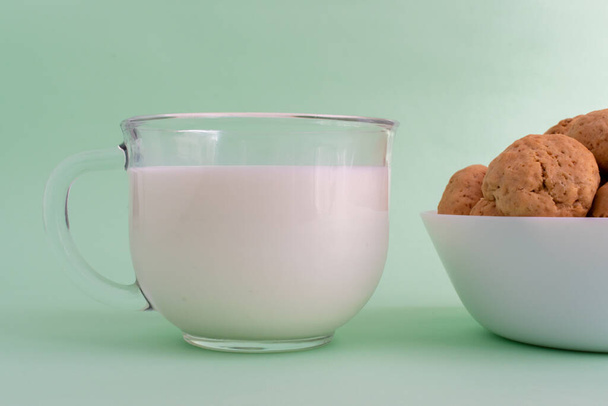 Szklankę mleka na zielonym tle. Koncepcja zdrowego odżywiania i gotowania ciasteczek. Wysokiej jakości zdjęcie - Zdjęcie, obraz
