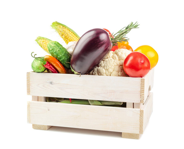 Různé čerstvé zeleniny v dřevěné krabici izolované na bílém pozadí. Prezentovány jsou rajčata, paprika, květák, chilli paprika, česnek, lilek, okurky, kukuřice a rozmarýn. - Fotografie, Obrázek