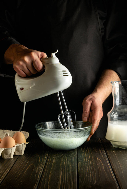 O chef profissional usa um misturador elétrico portátil para preparar um delicioso café da manhã ou almoço com ovos e leite. Ideia de menu para um restaurante ou hotel - Foto, Imagem