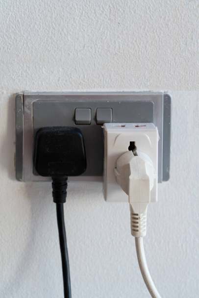 Fechar de dois plugues elétricos de aparelhos elétricos inseridos em tomadas elétricas na parede. - Foto, Imagem
