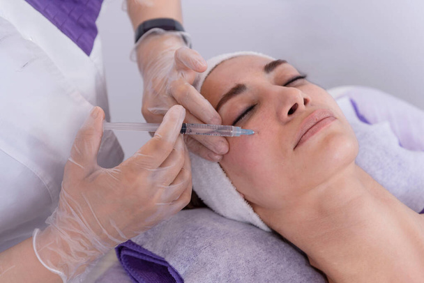 portrait of a young woman receiving facial mesotherapy treatment to smooth wrinkles. an anti-aging injection to firm up the skin - Photo, Image