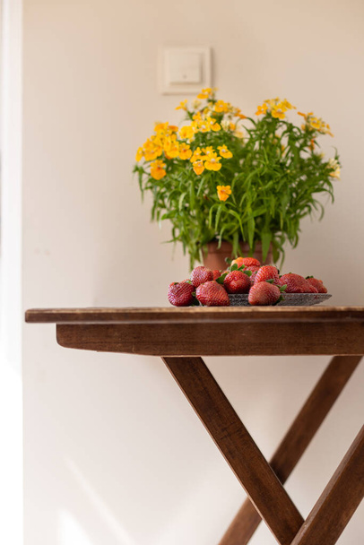 Morangos maduros e plantas em vaso em uma mesa de madeira, colheita de baga, deliciosos doces naturais - Foto, Imagem