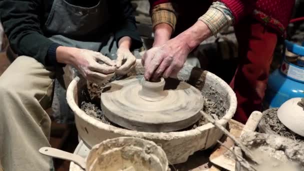 manos del maestro alfarero y aprendices aprenden a formar arcilla en el molde en la rueda de alfarero - Metraje, vídeo