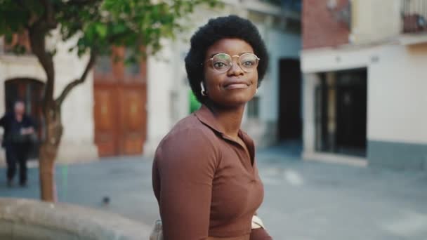 Afrikai lány szemüvegben élvezze a jó zenét vezeték nélküli fülhallgató a szabadban. Elég sötét bőrű nő pihen az utcán. - Felvétel, videó