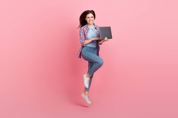 Full size photo of jumping business lady working on new project in her netbook isolated on pink color background. - Foto, imagen
