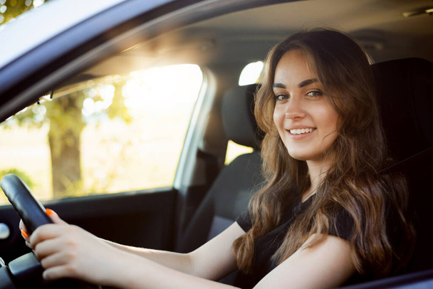 Onnellinen naispuolinen opiskelija ajaa autoa heti saatuaan auton lisenssin, mielellään läpäistä ajokoe ja ajaa autoa itse - Valokuva, kuva