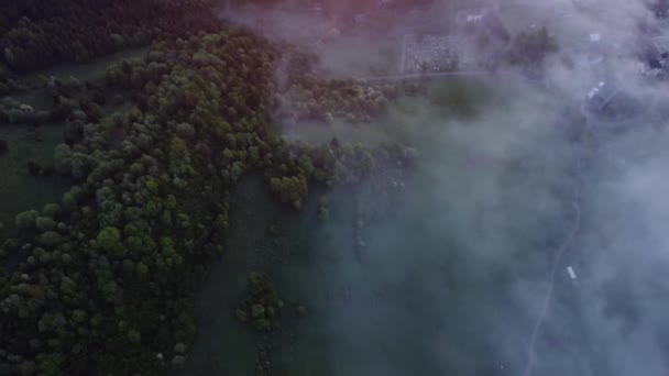 Blick von oben, verschwindender Nebel im Tal unter dem grünen Frühlingswald. Die Straße ist in Nebel gehüllt. Hochwertiges FullHD-Filmmaterial - Filmmaterial, Video
