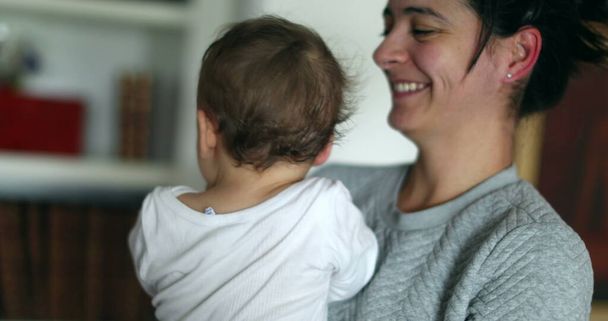 Madre casuale che tiene il bambino in braccio sorridente e ridente. Vita reale candida ridere e sorridere - Foto, immagini