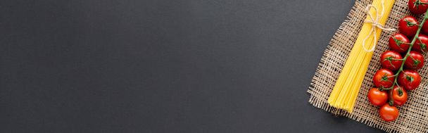 Κάτοψη της βιολογικής τοματίνια και ωμά μακαρόνια σε σάκο σε μαύρο φόντο, πανό  - Φωτογραφία, εικόνα