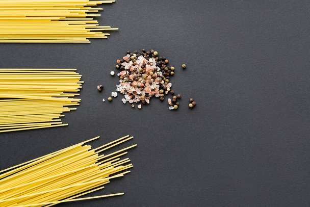 Top view of raw spaghetti and spices on black background  - Фото, изображение