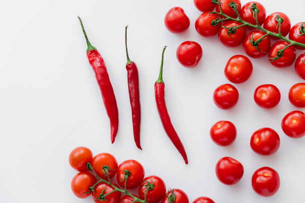 Top view of chili peppers near fresh cherry tomatoes on white background  - Fotoğraf, Görsel