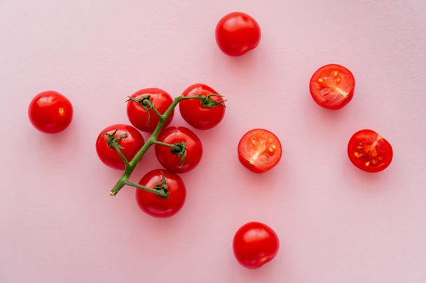 Top view of whole and cut cherry tomatoes on pink background  - Фото, изображение