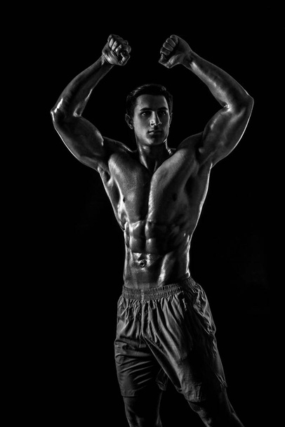 Musculoso y en forma joven culturista fitness modelo masculino posando sobre fondo negro. Estudio filmado sobre fondo negro. Blanco y negro, b w - Foto, Imagen