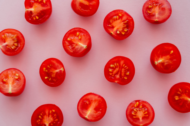 Vista superior de tomates cherry cortados sobre fondo rosa  - Foto, imagen