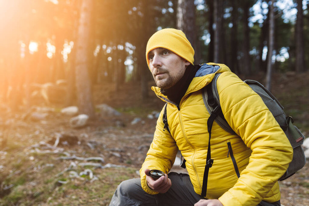młody biały Backpacker człowiek, z kompasem w przyrodzie o zachodzie słońca w pobliżu rzeki, trekking - koncepcja zaginionego człowieka - - Zdjęcie, obraz