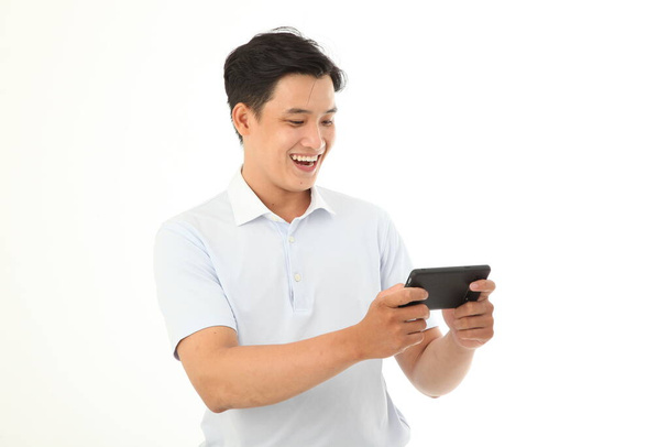 Asian handsome and cheerful young man play game or watch video on smart phone, isolated on background - Foto, afbeelding