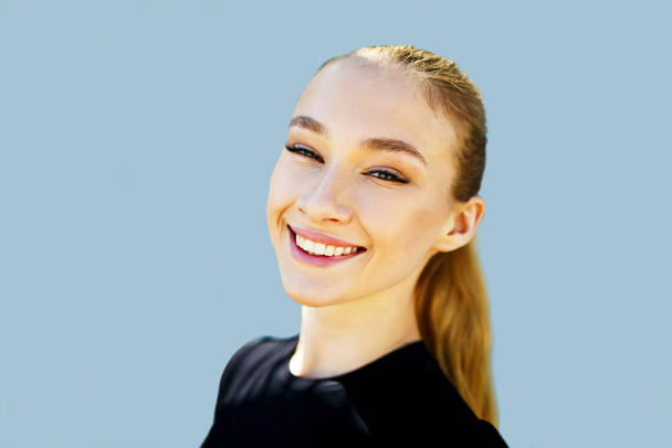 Glücklich lachende junge Frau mit perfekter Haut, natürlichem Make-up und schönem Lächeln. Frauenporträt mit weißen Zähnen auf blauem Hintergrund. - Foto, Bild