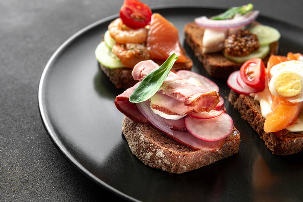 Cocina tradicional danesa. El clásico plato del sándwich de smorrebrod abierto sobre fondo oscuro - Foto, Imagen