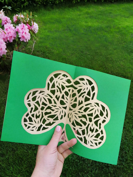 Řezání papíru ze zeleného jetelového shamrocku ručně. Zahajovací práce s irskou rostlinou opouští papírenské umění, krok za krokem dílna. Plochý pohled nahoru. - Fotografie, Obrázek