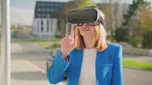 Business woman wearing professional virtual reality headset and gestures in augmented reality staying near business center, front view - Footage, Video