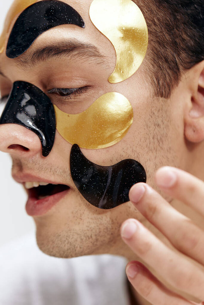 portrait of a man black and gold patches on the face health cosmetology skin care. High quality photo - Foto, afbeelding