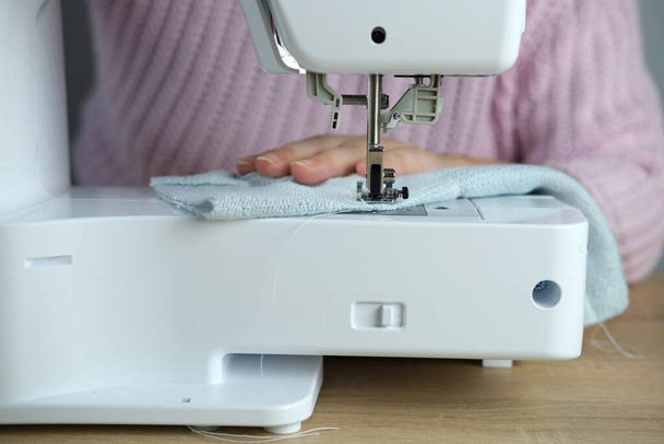 close-up of female hands perform work on a white sewing electric computer machine, stitches appear step by step on the fabric, concept of tailoring, women's hobby, modern needlework - Foto, immagini