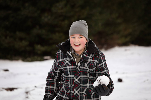 Boy in the snow with snow ball having snowball fight - Photo, Image