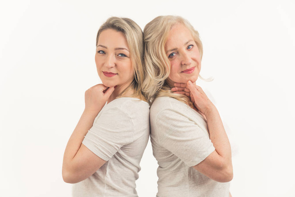 dwie blondynki europejskie stojące tyłem do tyłu średnie zbliżenie białe tło studio nakręciło kobiecą koncepcję. Wysokiej jakości zdjęcie - Zdjęcie, obraz