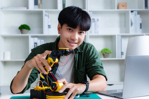 Asian teenager constructing robot arm homework project in house. technology of robotics programing and STEM education concept. - Photo, Image