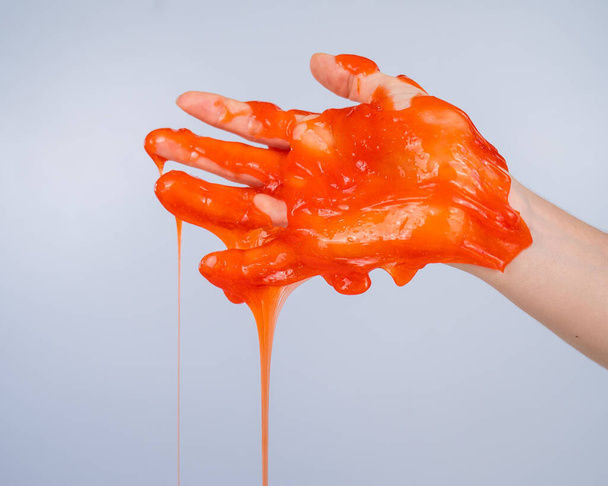 Red slime flowing down from a womans hand on a white background - Foto, Imagen