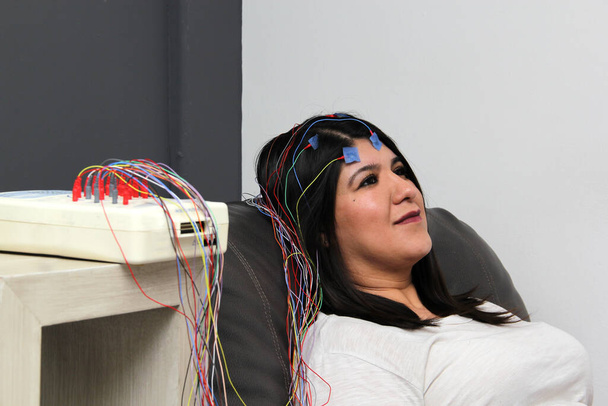 Mujer adulta latina es una paciente en la consulta de neurología y se realiza un estudio electroencefalográfico para ver la actividad eléctrica del cerebro - Foto, imagen