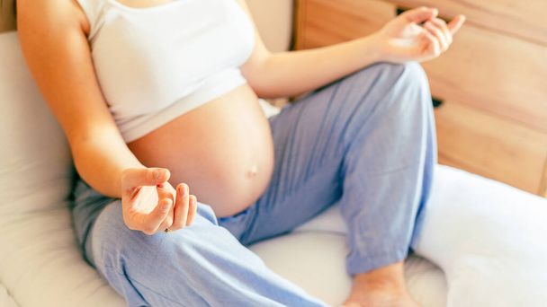 Διαλογισμός ικανότητας εγκυμοσύνης. Γιόγκα στο σπίτι. Νεαρή έγκυος μητέρα διαλογίζεται ενώ κάθεται σε στάση λωτού. Εγκυμοσύνη, ιατρική, φαρμακευτική, υγειονομική περίθαλψη έννοια - Φωτογραφία, εικόνα