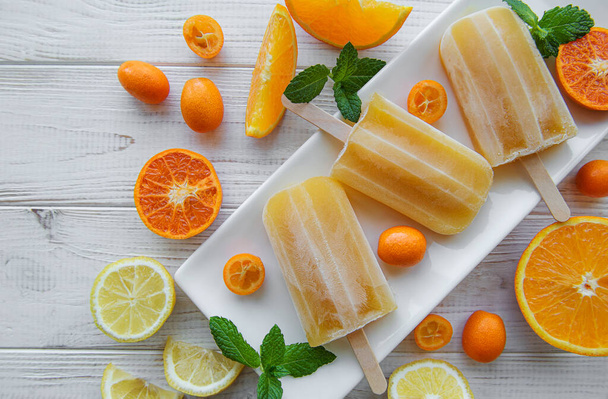 Fruit orange ice popsicle, ice cubes and slices of citrus fruits.  - Foto, afbeelding