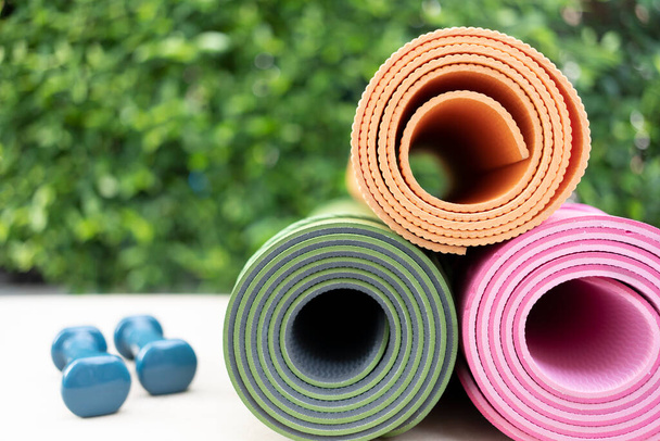 close up of colorful yoga mat and dumbble on the table, sport and healthy concept - Foto, afbeelding