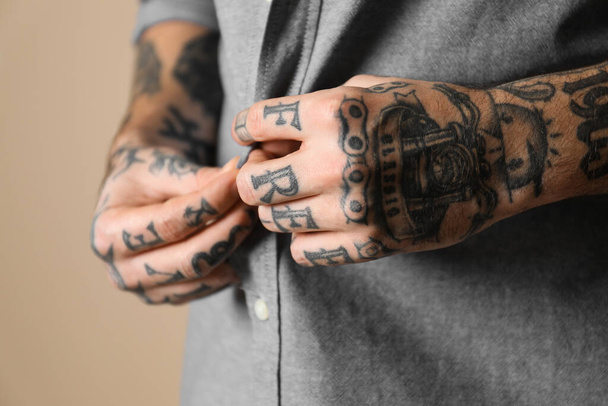 Young man with tattoos on body against beige background, closeup - Zdjęcie, obraz