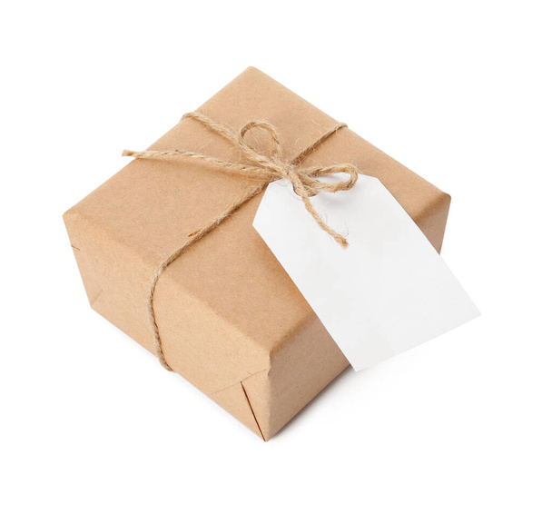 Gift box wrapped in kraft paper with bow and tag isolated on white - Fotó, kép