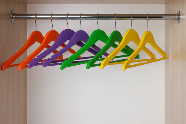 Set of bright clothes hangers on wardrobe rail - Foto, afbeelding