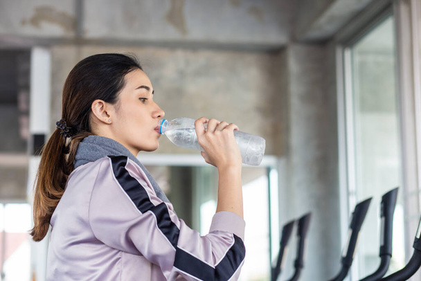 Sport women drinking water aftter burn out on bicycle in fitness gym healthy lifestyle - Foto, Imagem
