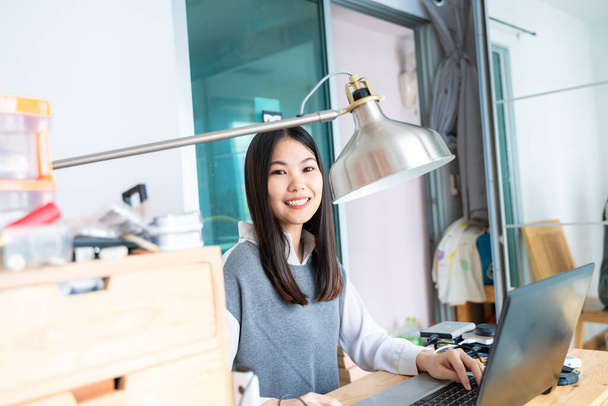 Молодая симпатичная азиатская деловая женщина с блокнотом в домашнем офисе - Фото, изображение