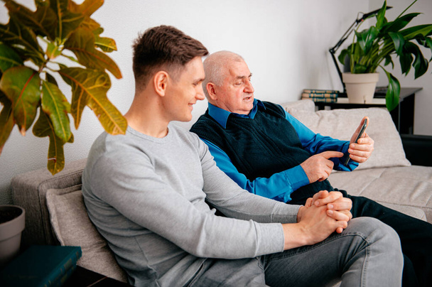 Grandson grandfather teaches use Smartphone at home - Zdjęcie, obraz