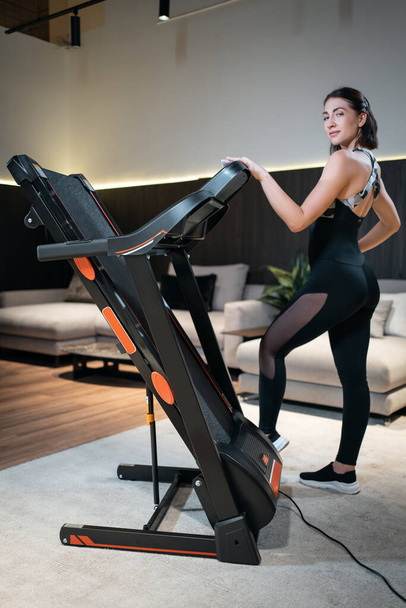athletic woman staying by assembled treadmill at home - Φωτογραφία, εικόνα
