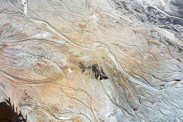 Abstracte achtergrond of textuur met een golvend patroon van aarde en water, water dat op de grond stroomt, een prachtig natuurlijk patroon van grote hoogte, een kunstmatig meer - Foto, afbeelding