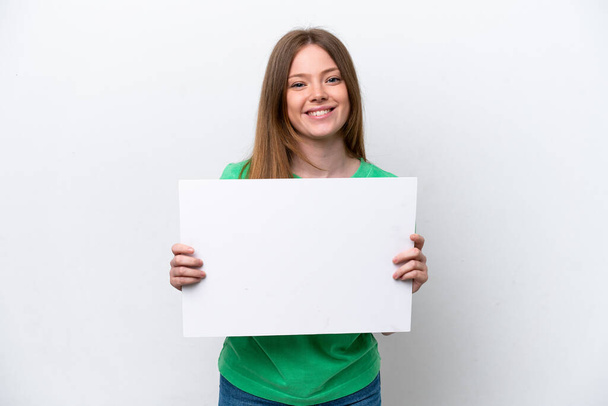 Mulher caucasiana jovem isolado no fundo branco segurando um cartaz vazio com expressão feliz - Foto, Imagem