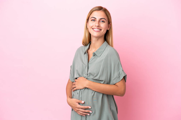 Young Uruguayan woman isolated on blue background pregnant and happy - 写真・画像