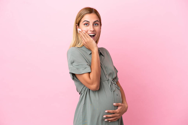 Νεαρή Ουρουγουανή γυναίκα απομονωμένη σε μπλε φόντο έγκυος και να κάνει χειρονομία έκπληξη - Φωτογραφία, εικόνα