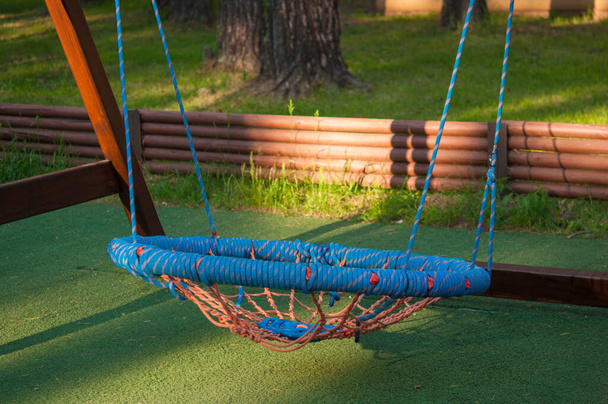 Hanging rope swing near the house. A place for relaxation and solitude. Comfortable hammock chair. Cozy exterior backyard. Concept of rest outdoor. - Foto, Imagen