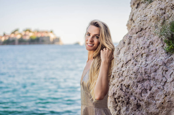 Woman tourist on background of beautiful view of the island of St. Stephen, Sveti Stefan on the Budva Riviera, Budva, Montenegro. Travel to Montenegro concept. - Photo, image