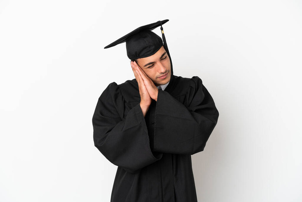 Young university graduate over isolated white background making sleep gesture in dorable expression - Foto, Imagem