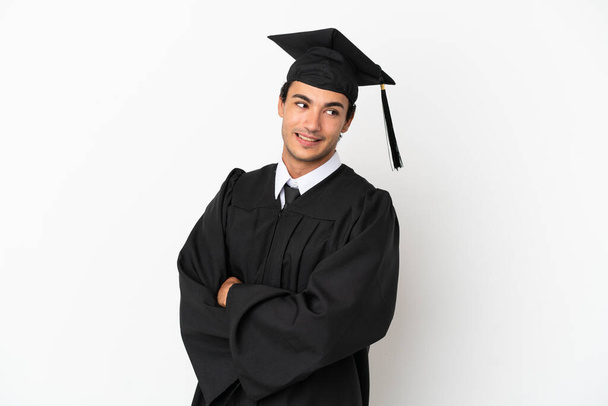 Young university graduate over isolated white background with arms crossed and happy - Φωτογραφία, εικόνα